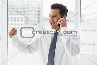 Cheerful businessman using cellphone in office
