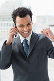 Cheerful elegant businessman using cellphone in office