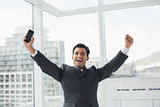 Elegant young businessman cheering in office