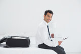 Businessman with cup and newspaper by luggage at a hotel room