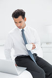 Businessman with coffee cup using laptop at hotel room