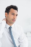Businessman suffering from neck pain in bed