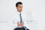 Businessman with stomach pain sitting on bed