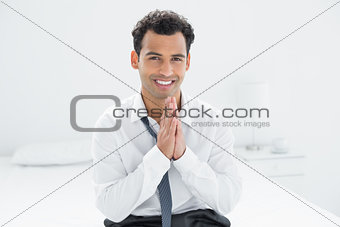 Portrait of a smiling businessman sitting on bed