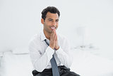 Happy thoughtful businessman sitting on bed
