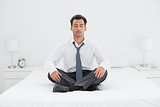 Relaxed well dressed man sitting with eyes closed on bed