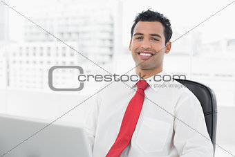 Smiling young businessman with laptop at office