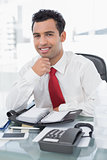 Smiling young businessman with diary sitting at office