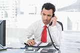 Businessman with diary using land line phone at office