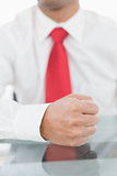 Mid section of a businessman with clenched fist on desk