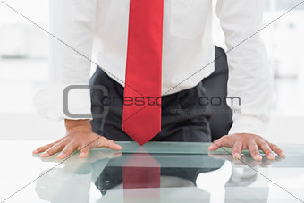 Mid section of a businessman with hands on desk