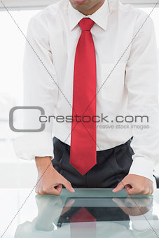 Mid section of a well dressed businessman with clenched fists on desk