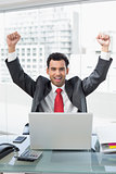 Businessman cheering in front of laptop at office