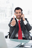Businessman gesturing thumbs up while on call at office desk