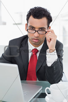 Upset businessman with laptop sitting at office desk