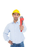 Handsome young handyman holding out a pipe wrench