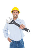 Portrait of a smiling handyman holding out wrench