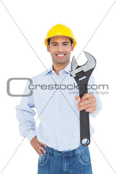 Smiling young handyman holding out a wrench