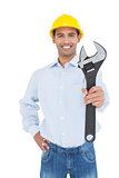 Smiling young handyman holding out a wrench