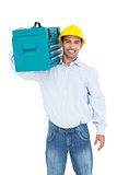 Portrait of a smiling handyman in hard hat carrying a toolbox