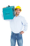 Portrait of a smiling handyman in hard hat carrying a toolbox