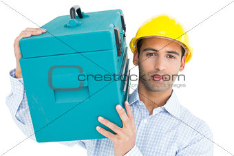 Portrait of a serious handyman in hard hat carrying a toolbox