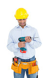 Smiling handsome young handyman looking at drill