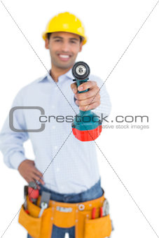 Smiling handsome young handyman holding out drill