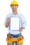 Smiling handyman in yellow hard hat holding a clipboard