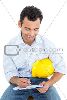 Handyman with yellow hard hat writing in clipboard