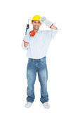 Smiling handsome young handyman in hard had with drill