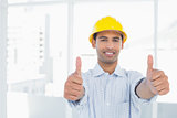 Smiling handyman in yellow hard hat gesturing thumbs
