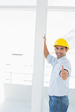 Handyman in yellow hard hat gesturing thumbs up in office