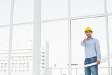 Architect in hard hat with blueprint gesturing thumbs up in office