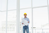 Architect in yellow hard hat with blueprint in office