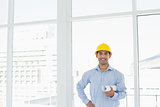Young architect in yellow hard hat with blueprint in office
