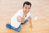 Smiling man cleaning the floor while gesturing thumbs up