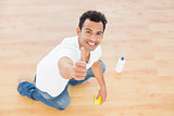 Smiling man cleaning the floor while gesturing thumbs up