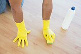 Yellow gloved hands with sponge cleaning the floor