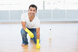 Smiling man cleaning the parquet floor at house