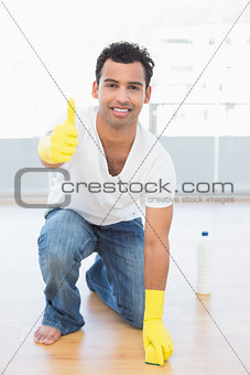 Smiling man cleaning the floor while gesturing okay sign