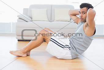 Young man doing abdominal crunches in the living room