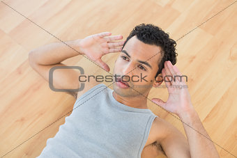 Young man doing abdominal crunches on parquet floor