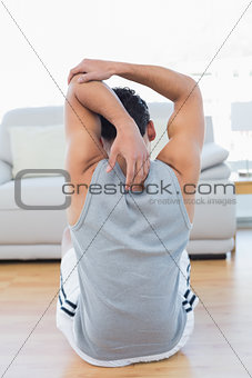 Man stretching hands behind back in the living room