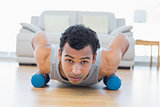 Man with dumbbells doing push ups in the living room