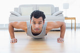 Sporty young man doing push ups in the living room