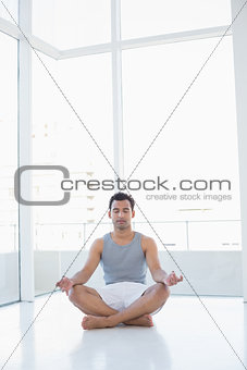 Full length of a young man sitting in lotus pose