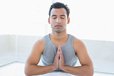 Young man meditating with eyes closed and joined hands
