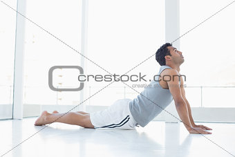 Fit young man doing the cobra pose in fitness studio