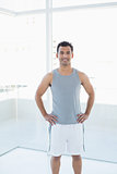 Fit man standing with hands on hips in fitness studio